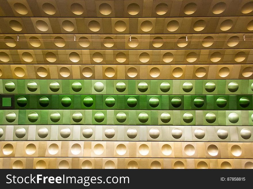 Metallic wall with circular shapes form a patter of different color shades in an metro station. Metallic wall with circular shapes form a patter of different color shades in an metro station.