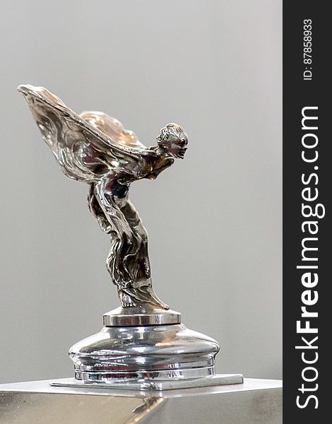 Iconic stainless-steel hood ornament on Rolls-Royce luxury car representing a winged woman leaning forward. Iconic stainless-steel hood ornament on Rolls-Royce luxury car representing a winged woman leaning forward.