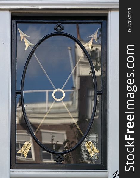 House window with cast iron frame and ornated with two gilded arrows with double points. House window with cast iron frame and ornated with two gilded arrows with double points