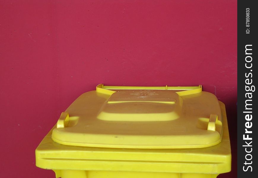 yellow-trash-bin-against-red-wall