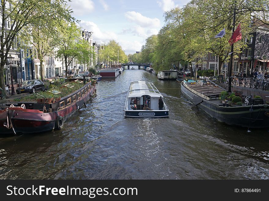 Prisengracht canal is the longest of the three main canals of Amsterdam. Here a tourist cruise boat passes along the Musem Boat &#x28;Hendrika Maria freighter&#x29;.