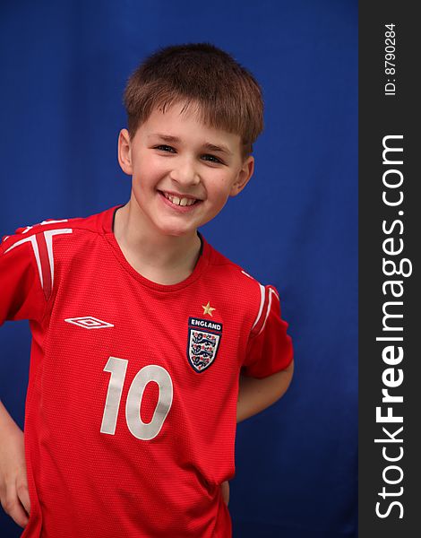 Happy young footballer in a red sport shirt on a dark blue background. Happy young footballer in a red sport shirt on a dark blue background