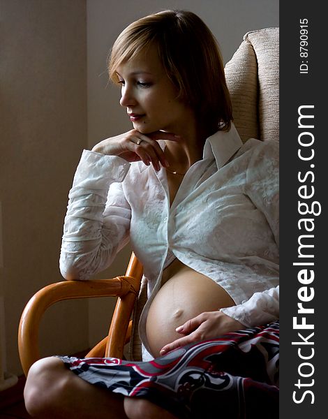 Beautiful pregnant woman sitting in armchair. Beautiful pregnant woman sitting in armchair