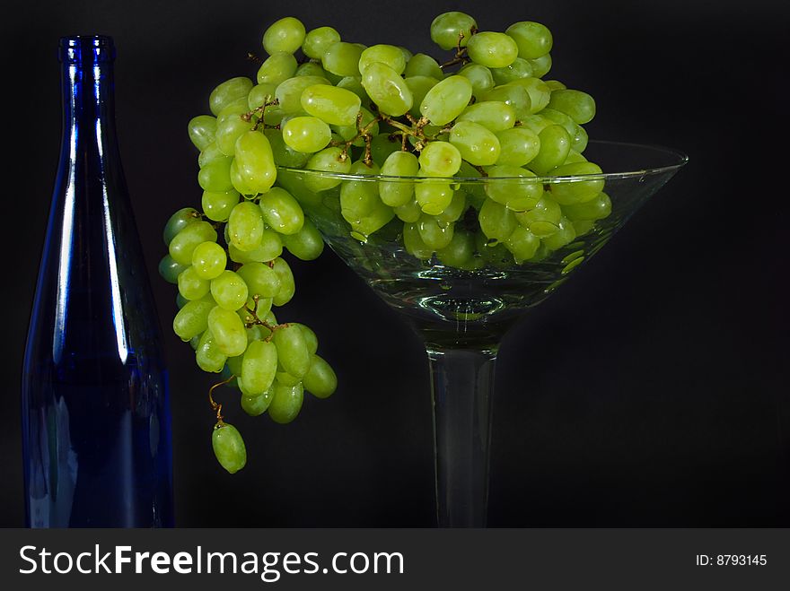 Blue wine bottle with a bunch of green grapes. Blue wine bottle with a bunch of green grapes.