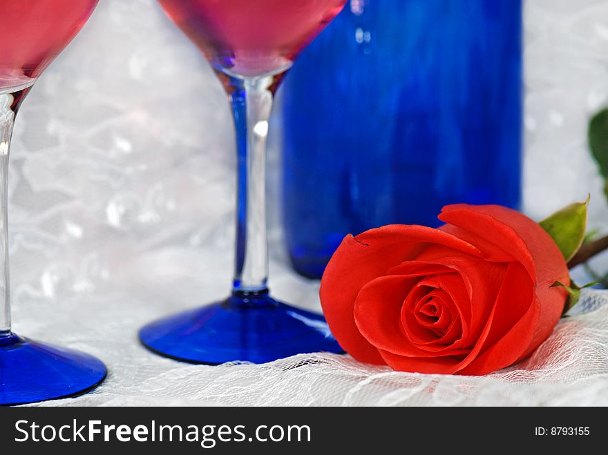 Bright rose with wine glasses and bottle on lace. Bright rose with wine glasses and bottle on lace.