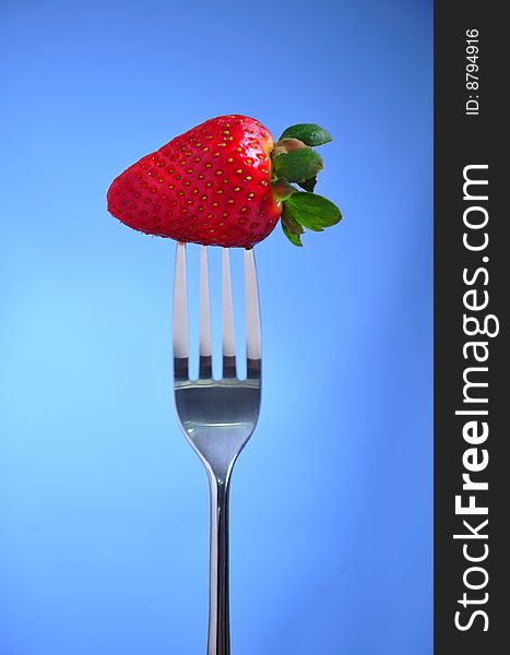 Strawberry on fork , blue background. Strawberry on fork , blue background