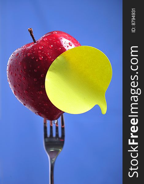 Red apple in fork with yellow note. Red apple in fork with yellow note