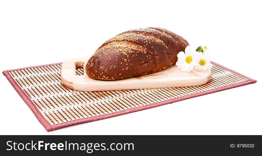 Rye bread and daisies on the cutting board, isolated. Rye bread and daisies on the cutting board, isolated