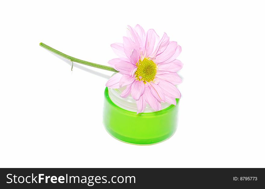 Green cream glass jar with nice spring pink flower isolated on the white. Green cream glass jar with nice spring pink flower isolated on the white.