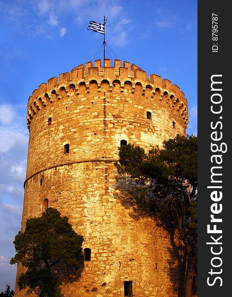 Ancient guard tower in Thessaloniki, Greece, known by the name of White Tower. Greek flag on top, clear sky. Ancient guard tower in Thessaloniki, Greece, known by the name of White Tower. Greek flag on top, clear sky.