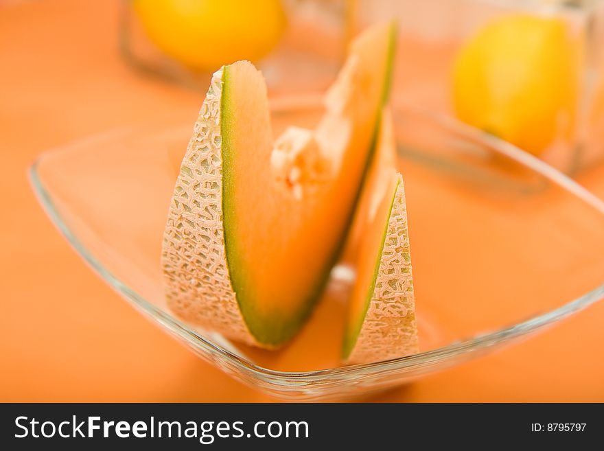 Cool cantaloupe melon wedges, ready for summer on orange in a glass bowl