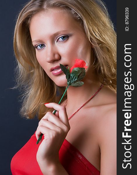 Beautiful girl with a flower in hands against a dark background. Beautiful girl with a flower in hands against a dark background