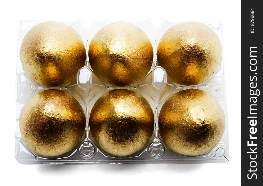 Six golden eggs in an egg carton isolated over white. Six golden eggs in an egg carton isolated over white