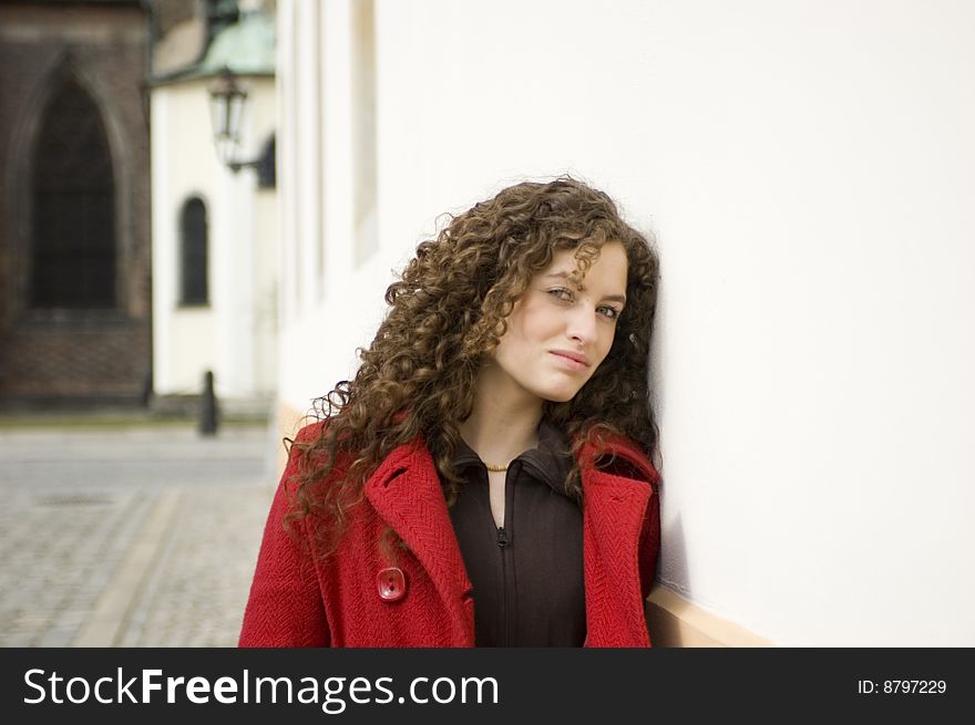 Teenage girl in Poland, portrait. Young girl with curly hairs wearing red coat, posing in Wroclaw city.