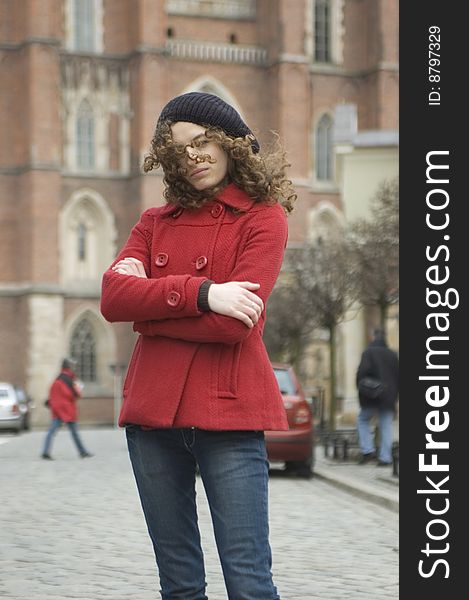 Teenage girl in Poland, portrait. Young girl with curly hairs wearing red coat, posing in Wroclaw city.