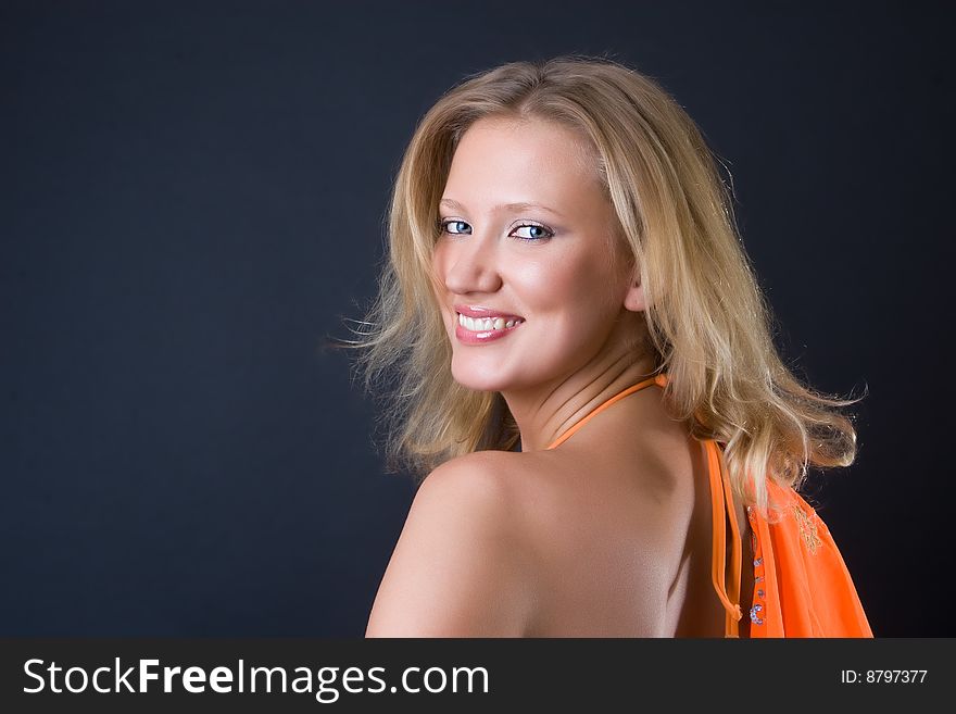 Beautiful girl in an orange bikini with a scarf against a dark background. Beautiful girl in an orange bikini with a scarf against a dark background