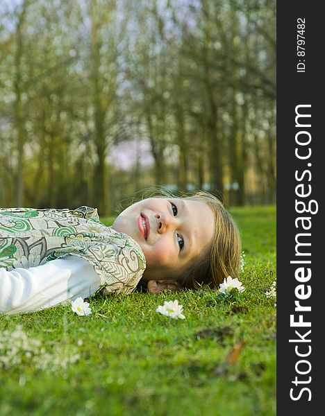 Image of a young girl lying on the grass in a park in spring. Image of a young girl lying on the grass in a park in spring.