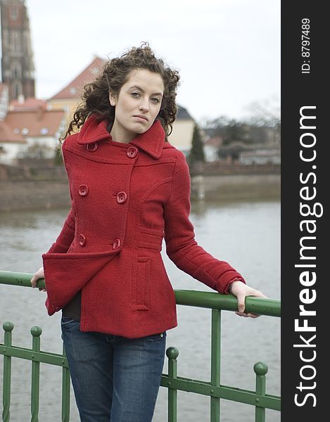 Teenage girl in Poland, portrait. Young girl with curly hairs wearing red coat, posing in Wroclaw city.