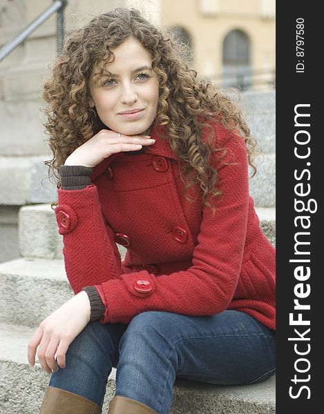 Teenage girl in Poland, portrait. Young girl with curly hairs wearing red coat, posing in Wroclaw city.