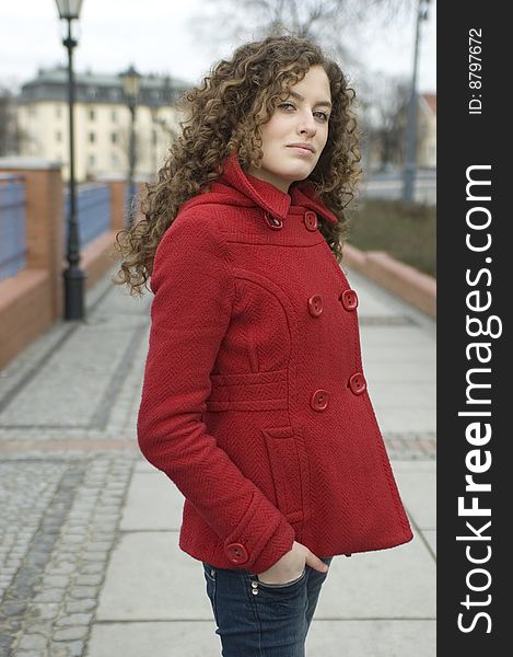 Teenage girl in Poland, portrait. Young girl with curly hairs wearing red coat, posing in Wroclaw city.