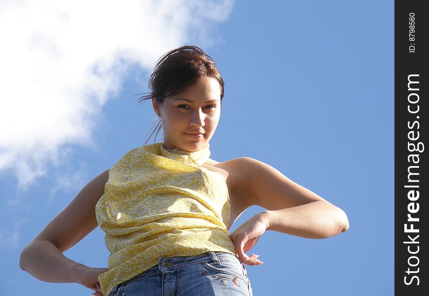 Girl in yellow clothes on a background blue sky with clouds