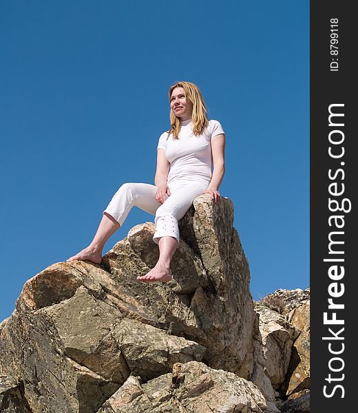 Woman in white sitting at rock. Woman in white sitting at rock