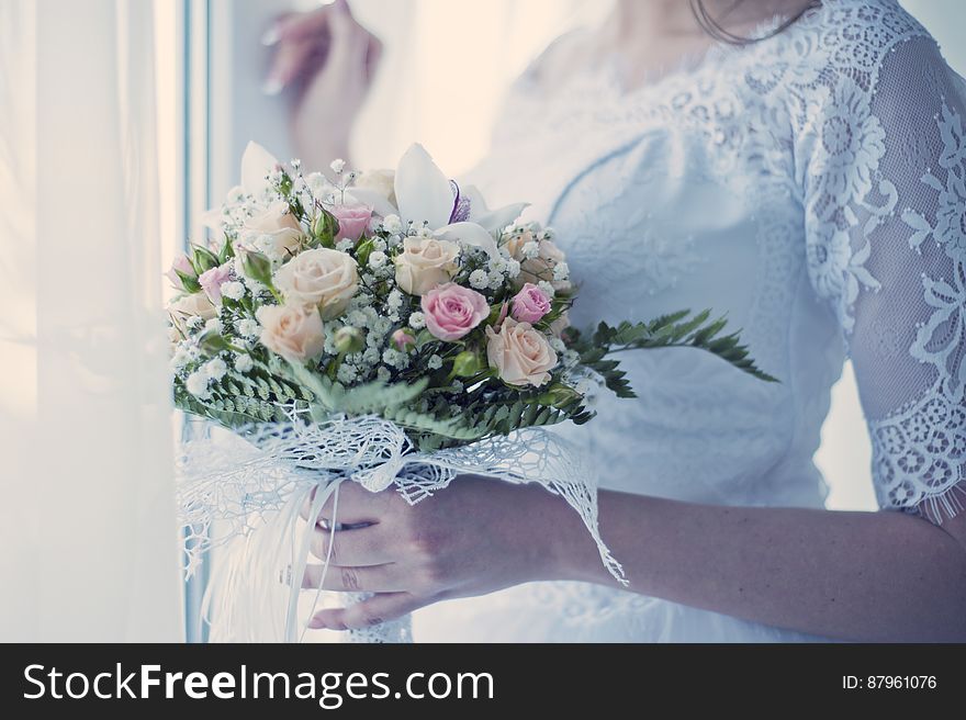 Close up of bride in white gown holding floral bouquet. Close up of bride in white gown holding floral bouquet.