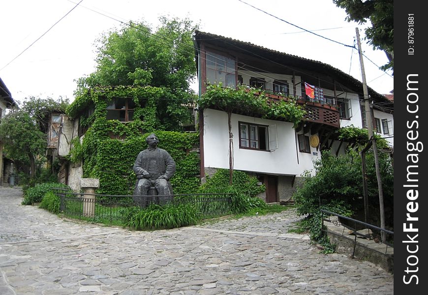 A house in traditional style and a statue in the garden. A house in traditional style and a statue in the garden.