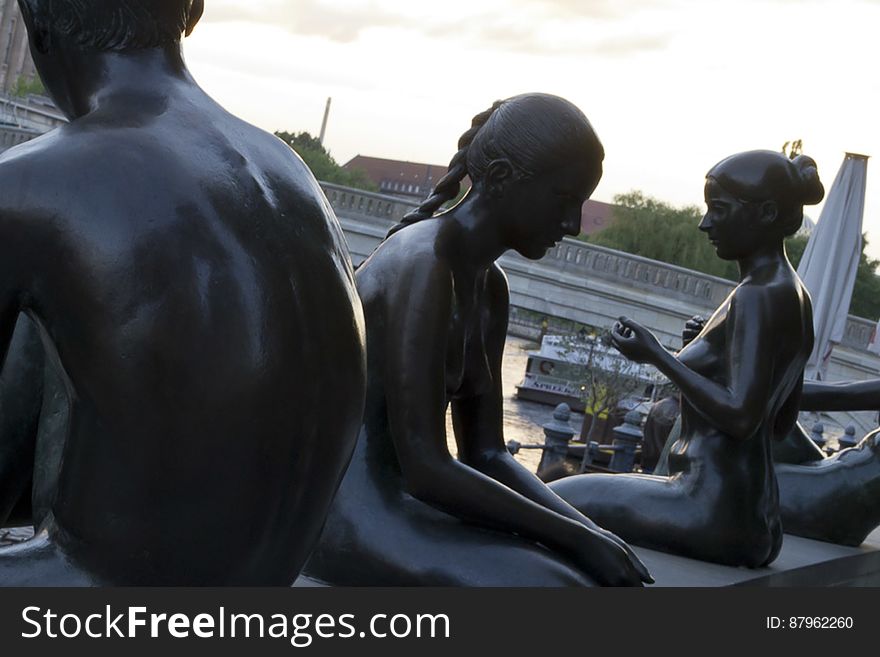 A trio of statues depicting a boy and three girls on the river Spree in Berlin, Germany. A trio of statues depicting a boy and three girls on the river Spree in Berlin, Germany.
