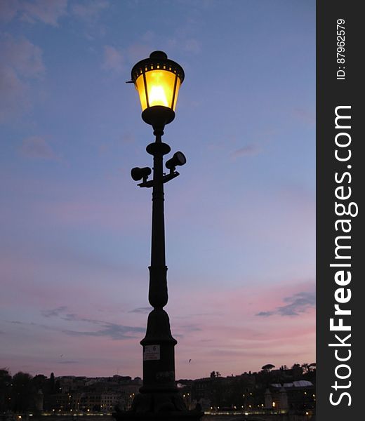 A street lamp with the light on at night. A street lamp with the light on at night.