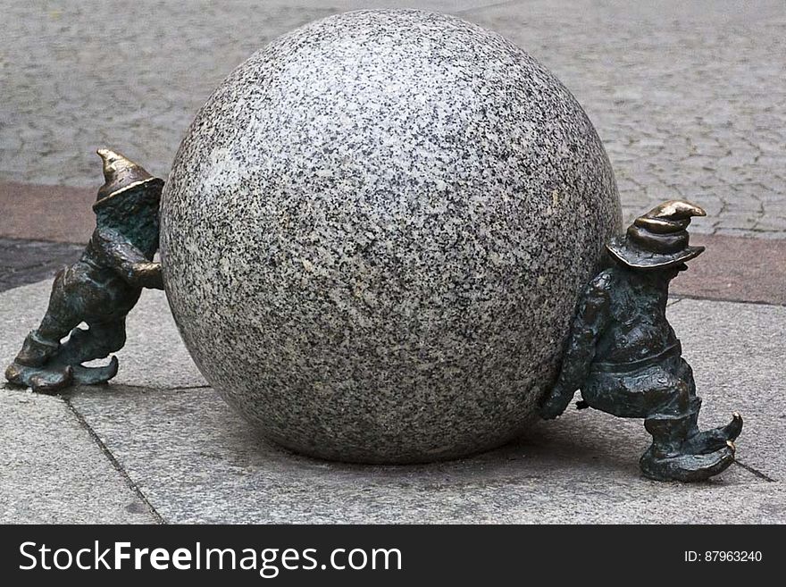 A sculpture of pair of gnomes rolling a stone. A sculpture of pair of gnomes rolling a stone.