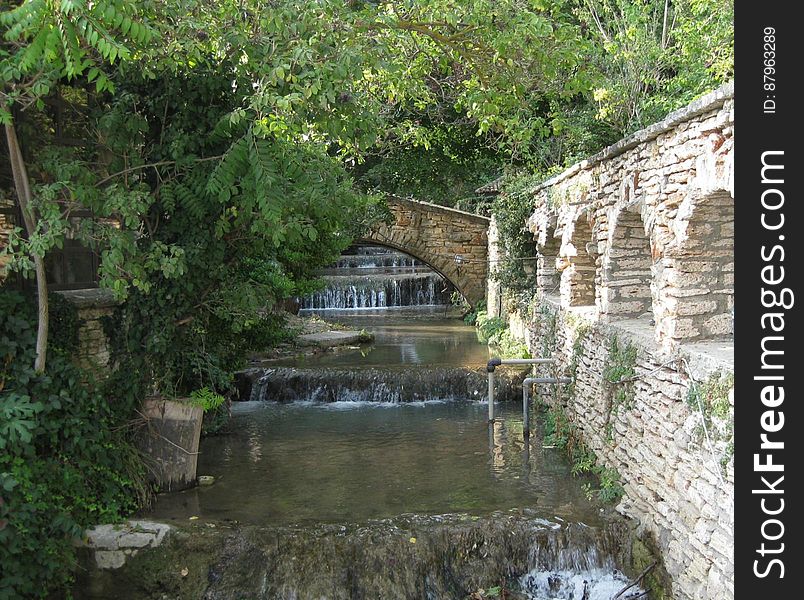 A cascading canal with riffles and a stone construction on the right bank.