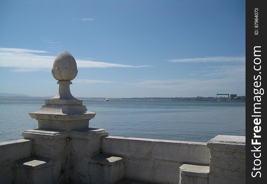 A stone sculpture on a banister overlooking the sea. A stone sculpture on a banister overlooking the sea.