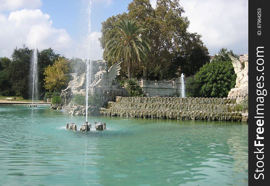 A view of a park with a large pool of water and fountain. A view of a park with a large pool of water and fountain.