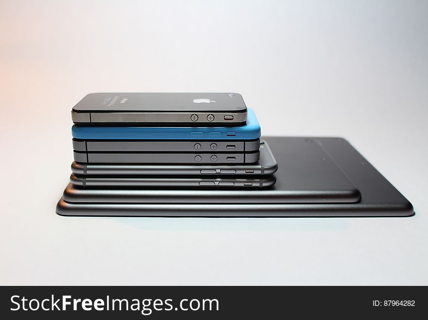 Different models of iPhone piled up on a white background. Different models of iPhone piled up on a white background.