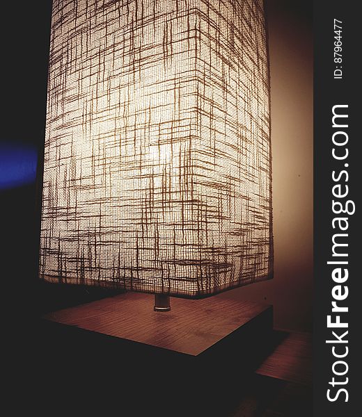 A close up of a modern lamp on a wooden table.