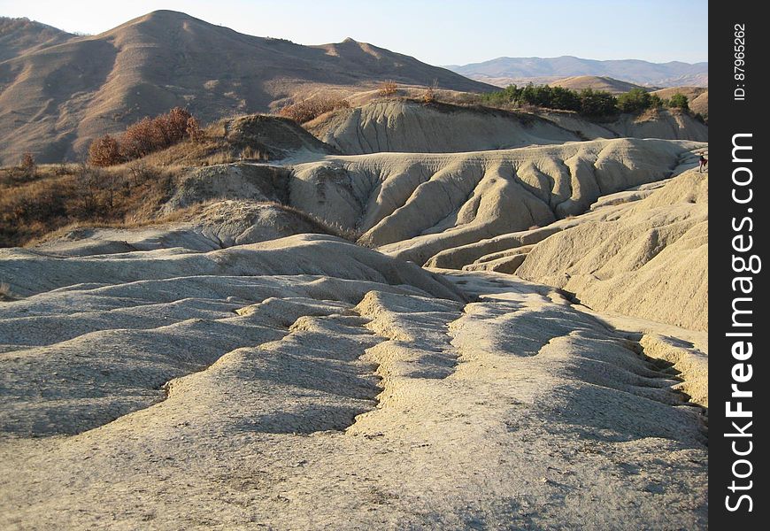 Sand dunes, hills and distant mountains in an arid climate with just a few trees surviving in the harsh conditions. Sand dunes, hills and distant mountains in an arid climate with just a few trees surviving in the harsh conditions.