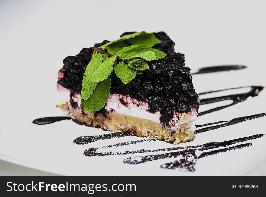 Slice of blackberry cheesecake with drizzle effect on white background.