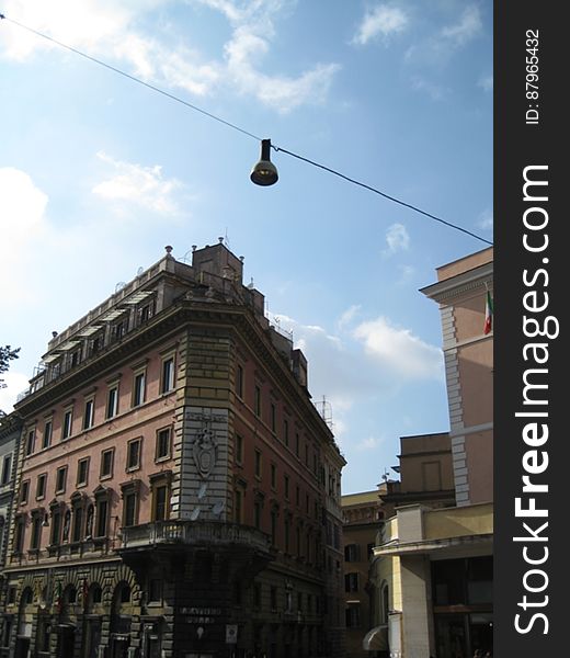 A historic building and a street lamp hanging on a cable stretched above the street. A historic building and a street lamp hanging on a cable stretched above the street.