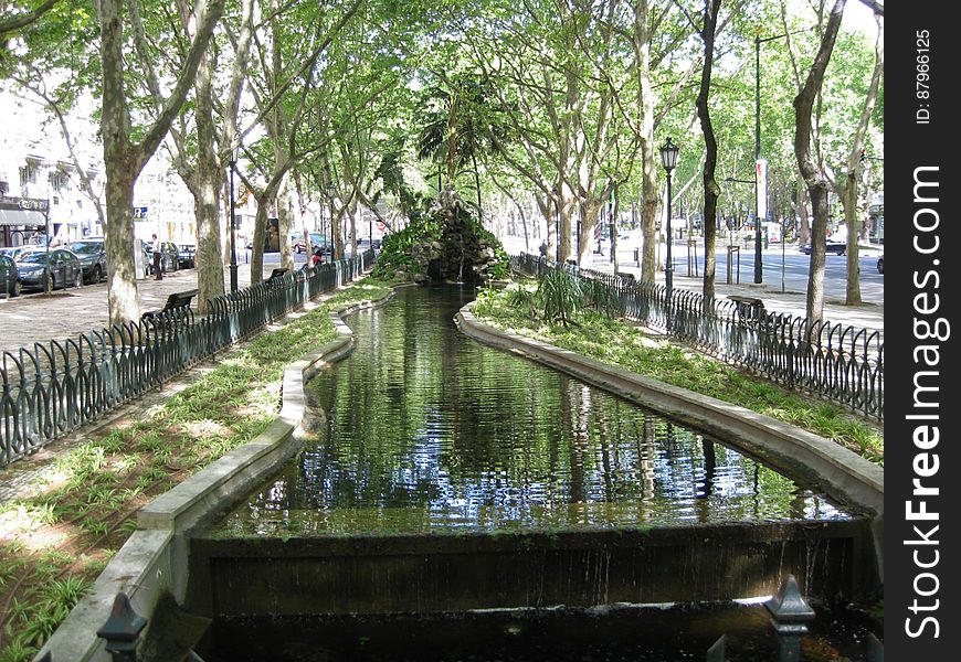 A canal flowing through a fenced park in a city. A canal flowing through a fenced park in a city.