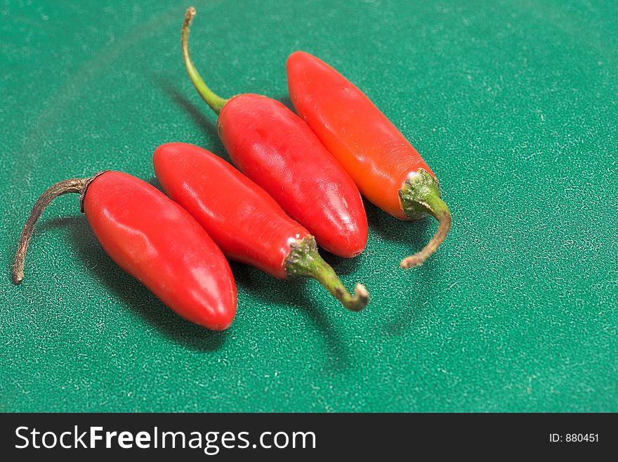 Four chilis in a row on green background. Four chilis in a row on green background