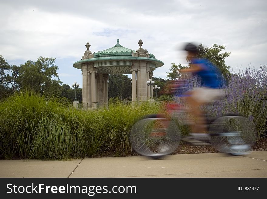 A bicyclist blurs by a pagoda in the background.