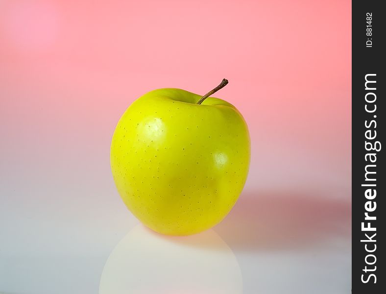 A yellow apple isolated in light pink background