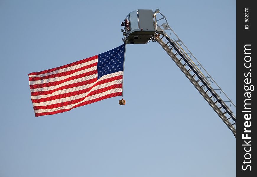 The American flag attached to a fire engine ladder waves straight out. The American flag attached to a fire engine ladder waves straight out.