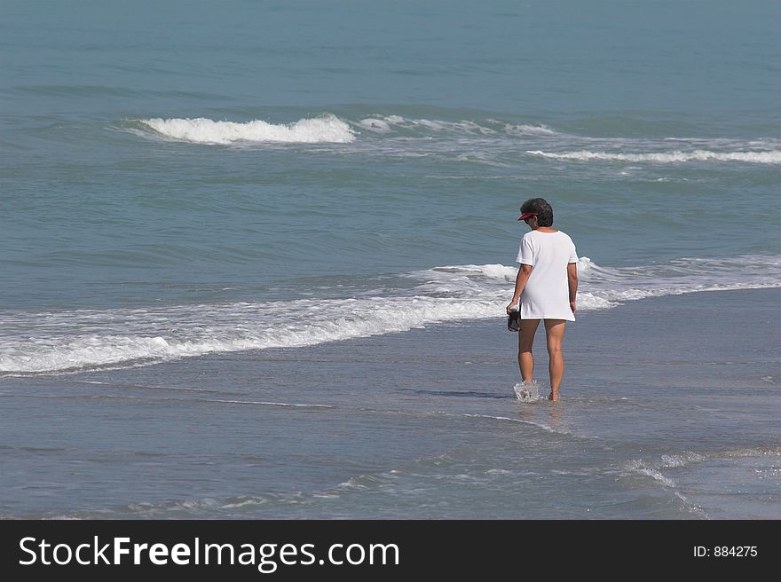 Woman enjoying the day walking alone ocean side. Woman enjoying the day walking alone ocean side