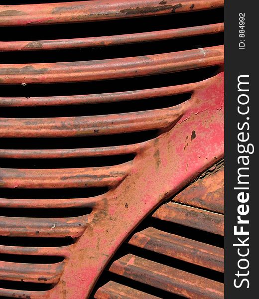 Grille work on the front of an old red truck.