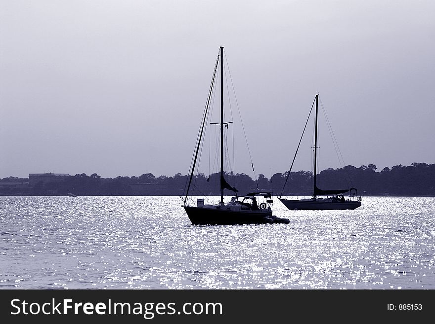 Blue tint monochrome of two sailboats in silhouette. Blue tint monochrome of two sailboats in silhouette