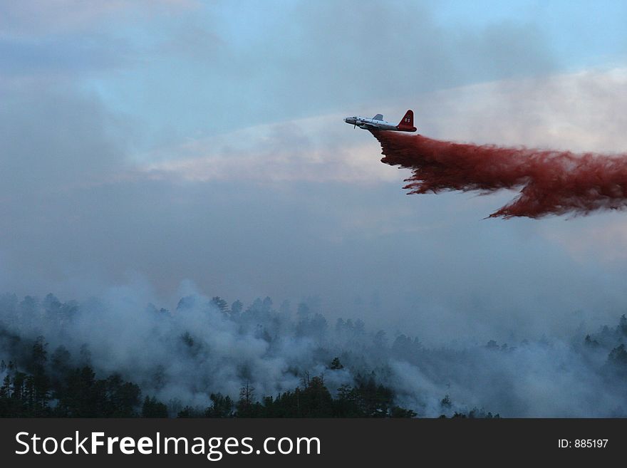 Slurry bomber dropping retardant on a forest fire