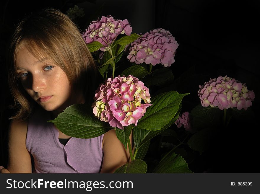 Beautiful little girl in flowers with dark background. Beautiful little girl in flowers with dark background