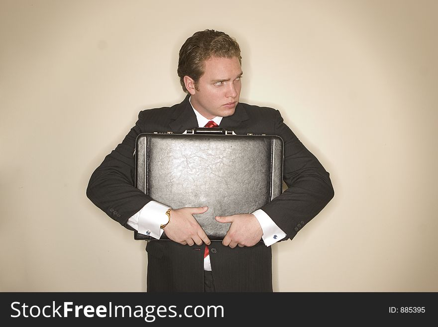 Business man in black suit, red tie, and white shirt is holding briefcase tightly